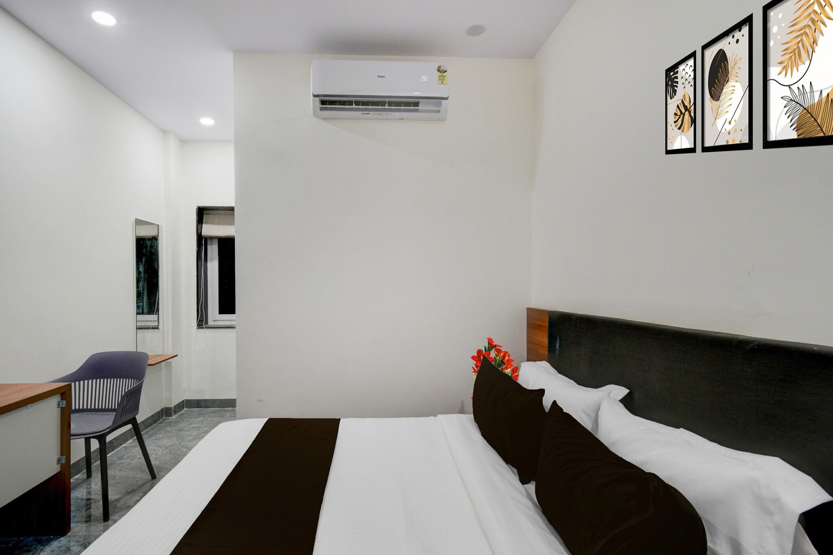 Ein Hotelzimmer mit Bett, Schreibtisch, Stuhl, Klimaanlage und Bildern an der Wand.