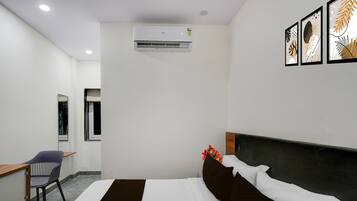 Ein Hotelzimmer mit Bett, Schreibtisch, Stuhl, Klimaanlage und Bildern an der Wand.