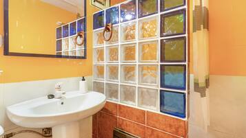 Un baño con un lavamanos blanco, un espejo y una pared de azulejos con un vitral.