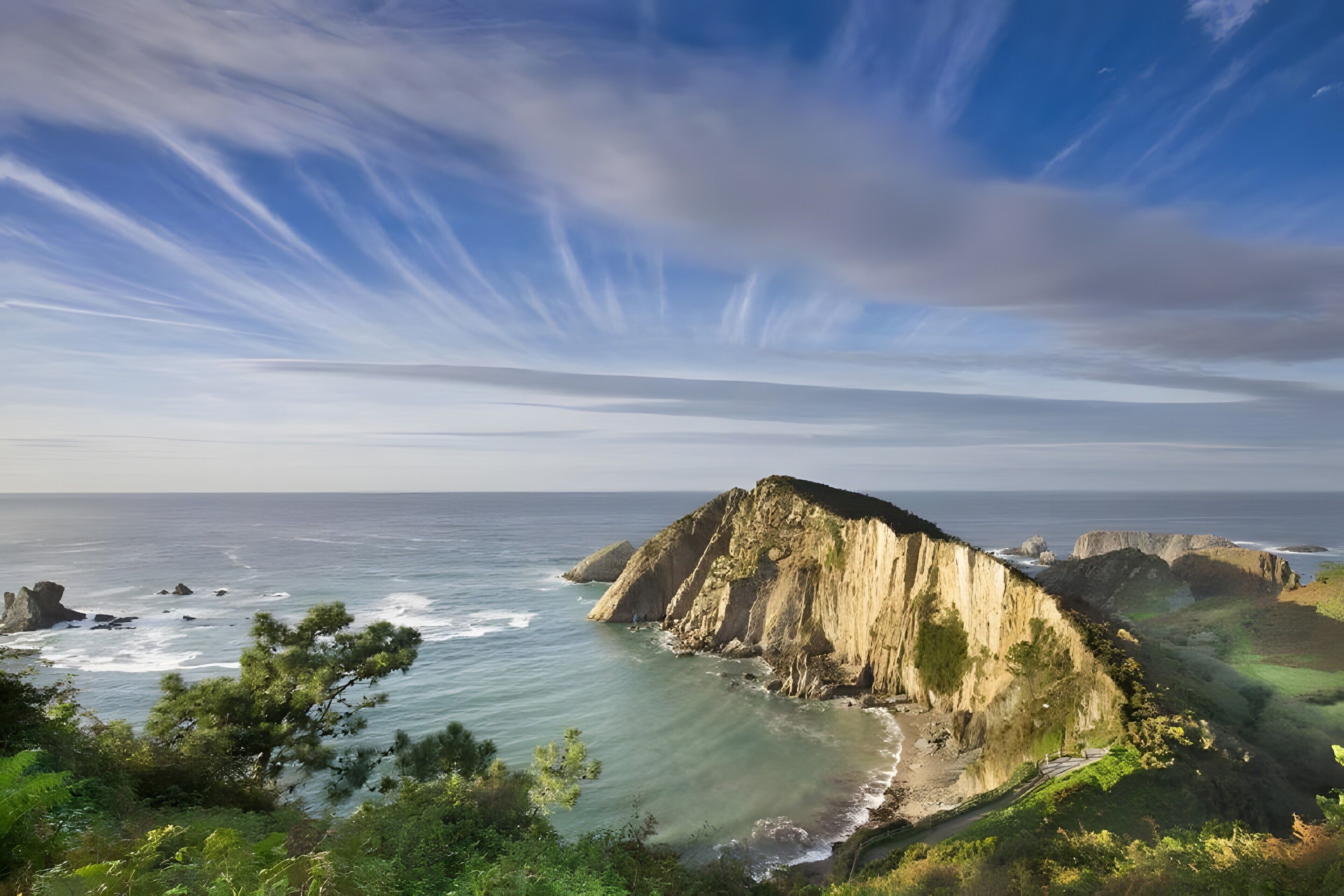 Paisagem costeira com falésias, uma praia e o oceano.