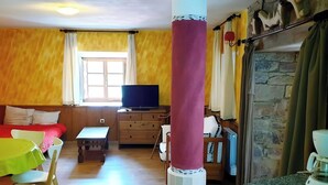 A room with a television on a wooden cabinet, a sofa, a table, and a coffee machine. - ‘Zentralclub La Osera’ Apartment with Mountain Views, Terrace & Shared Garden (Las Viñas)