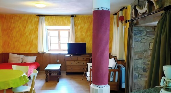 Una habitación con televisión sobre un mueble de madera, un sofá, una mesa y una cafetera.