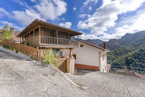 A chalet with a balcony, set against a mountainous backdrop. - ‘Zentralclub La Osera’ Apartment with Mountain Views, Terrace & Shared Garden (Las Viñas)
