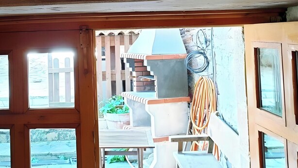 A wooden-framed window with a view of a balcony and outdoor area. - ‘Zentralclub La Osera’ Apartment with Mountain Views, Terrace & Shared Garden (Las Viñas)