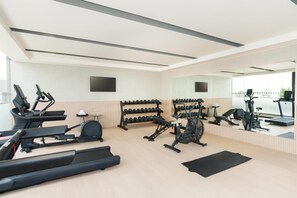 A modern gym with treadmills, elliptical machines, and a weight rack.