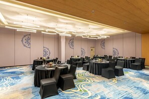 A conference room with round tables, black chairs, and a patterned carpet.