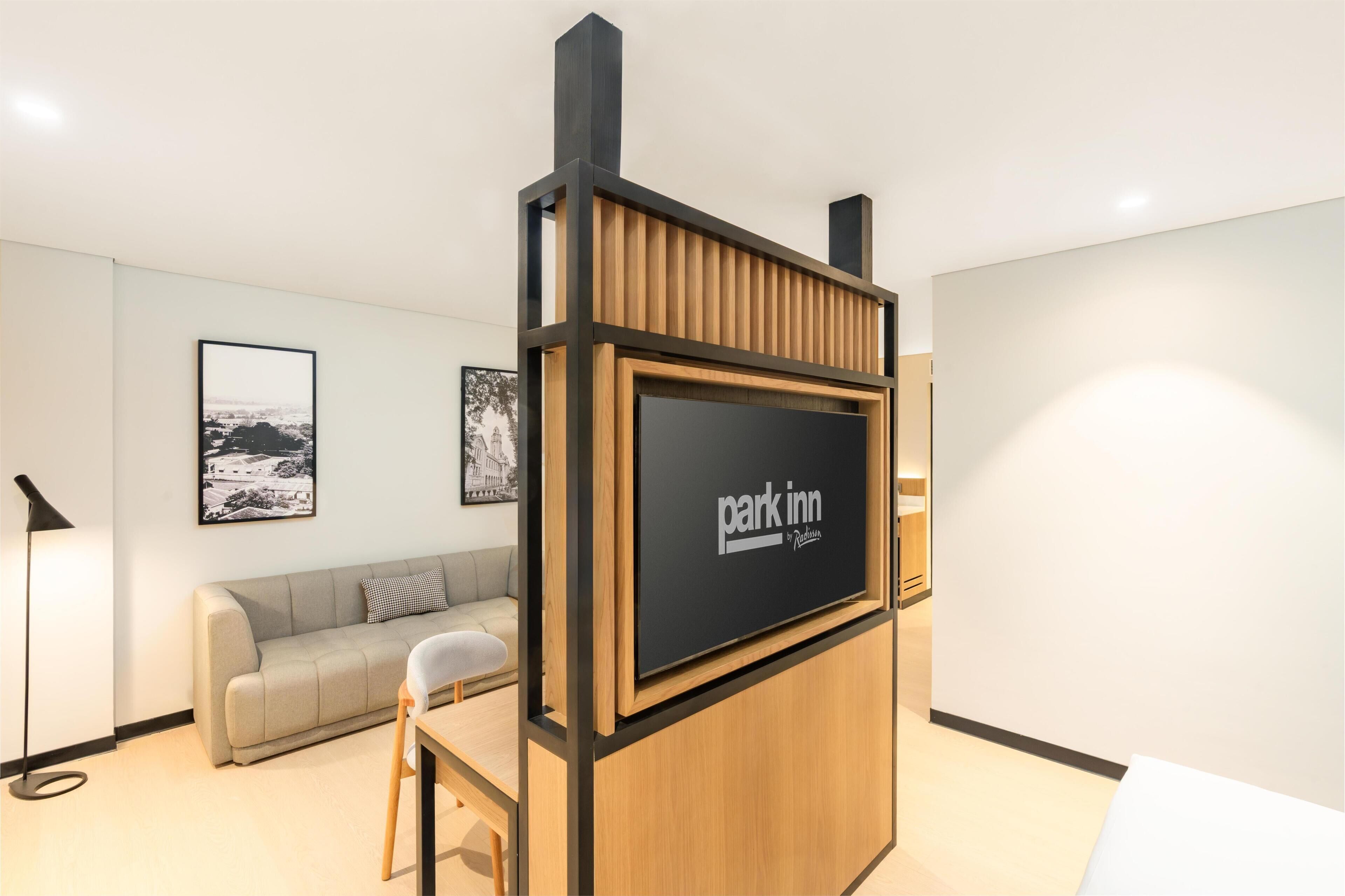 A modern room with a sofa, a table, and a TV screen displaying 'park inn by Radisson'.