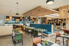A modern restaurant interior with booths, tables, and a bar area.