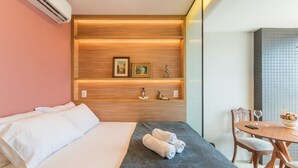 A hotel room with a bed, a small table with a vase, and a wall with shelves displaying decorative items. - Studio Near the Beach in Condo w/ Pool Edf0207 (Salvador)