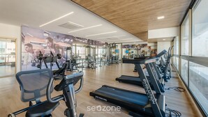 Un gimnasio con cintas de correr, bicicletas estáticas y máquinas de pesas.