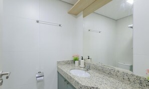 A bathroom with white tiles, a granite countertop, a sink, a mirror, and a towel rack. - Studio With Balcony and Oceanfront View - Edf1605 (Salvador)