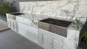 Uma cozinha com bancada de mármore, churrasqueira embutida e armários espaçosos.