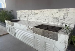 Eine Küche mit Marmorarbeitsplatte, integriertem Grill und Küchenschränken.