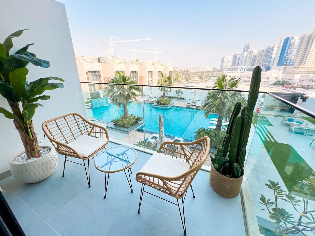 A balcony with wicker furniture, a pool, and a cactus plant.