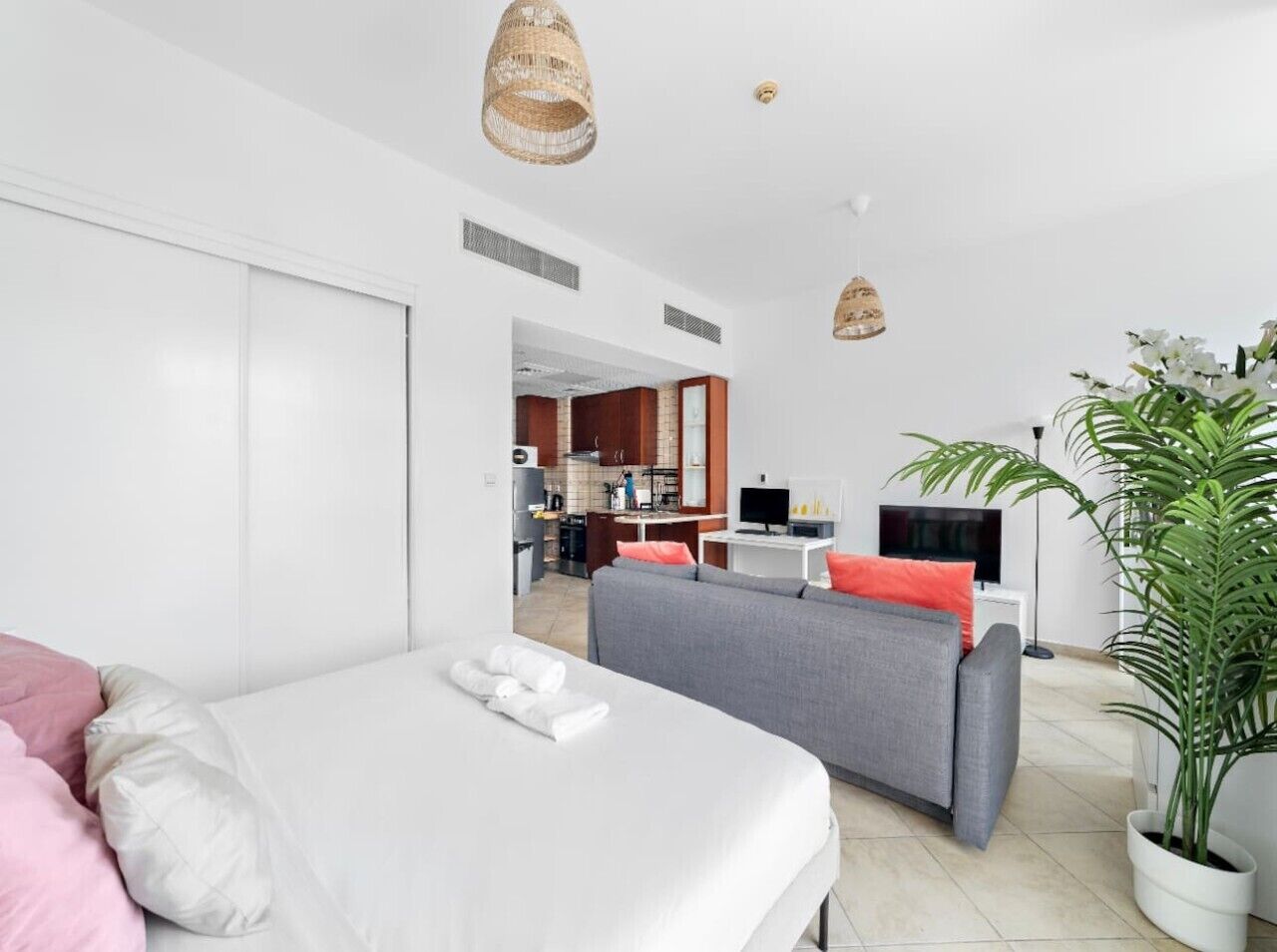 Une chambre d’hôtel moderne équipée d’un lit, d’un canapé, d’une télévision, d’un coin repas et d’une plante en pot.