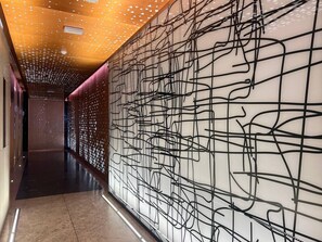 A hallway with a patterned wall and a ceiling with a geometric design. - Chic & Cozy Studio in JVC | Top Amenities & Views! (Dubai)