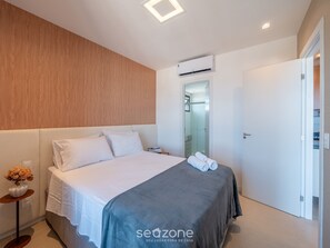 A modern hotel room with a bed, bedside table, and a door leading to a bathroom. - Apt w/ sea View, 800m fr/ the Beach Edf1306 (Salvador)