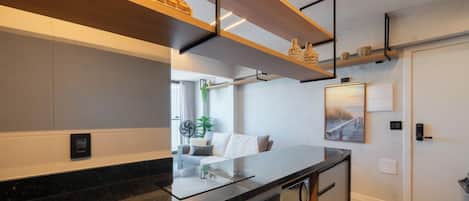 Cocina moderna con encimera negra, estantes de madera y vista a una playa por una ventana.