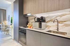 A modern kitchen with a built-in microwave, a coffee maker, and a stainless steel sink. - Modern Studio | Rooftop Infinity Pool | Arjan (Dubai)