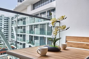 A balcony with a wooden table, two white cups, and a potted orchid plant. - Modern Studio | Rooftop Infinity Pool | Arjan (Dubai)