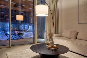 Ein modernes Wohnzimmer mit rundem Tisch, einer Couch und einem großen Fenster mit Vorhängen.