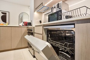 Eine kompakte Küche mit eingebautem Geschirrspüler, einer Mikrowelle und einem kleinen Backofen.