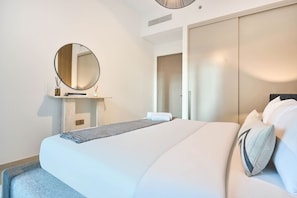 Ett modernt hotellrum med en stor säng, en rund spegel, ett sängbord och en garderob.