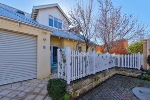 Una propietat residencial amb porta de garatge, valla blanca de pal i un camí de xemeneia de maó.