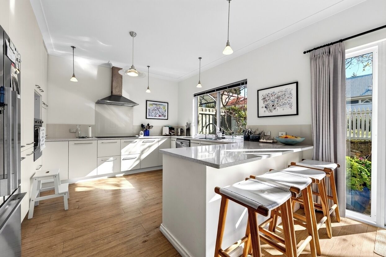 A modern kitchen with a central island, pendant lighting, and a view of the outdoors.