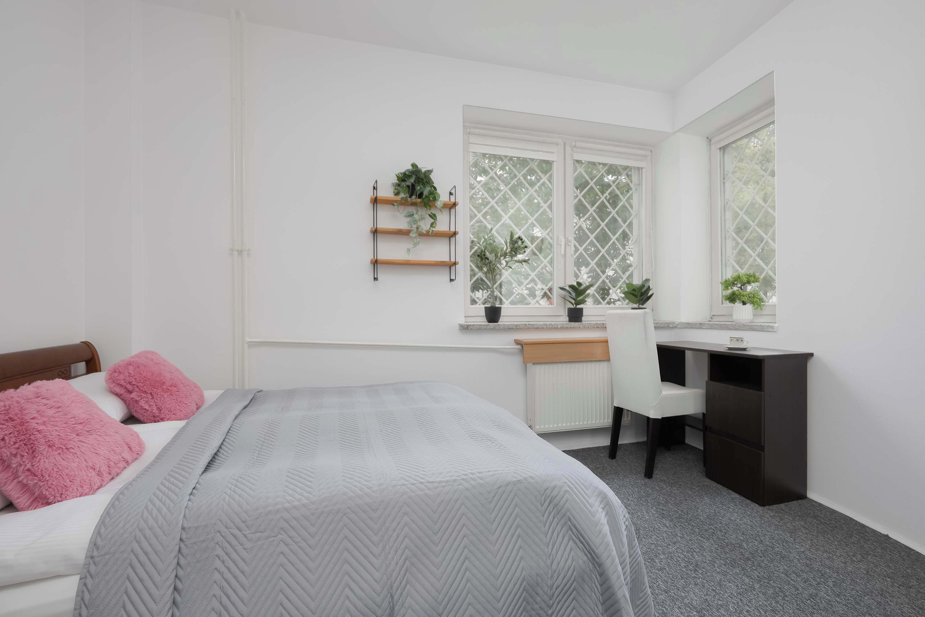Een slaapkamer met een bed, een bureau en een raam met uitzicht.