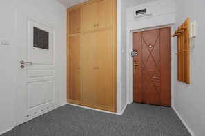 Un pasillo con una puerta blanca, un armario de madera y una puerta marrón con un tirador decorativo.