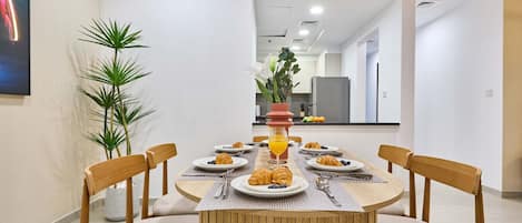 Un espace repas comprenant une table ronde, six chaises et une plante placée au centre.