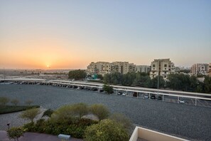 A parking lot with multiple cars and a building complex in the background. - Family-Friendly 2BR in Remraam with Pool View (Dubai)