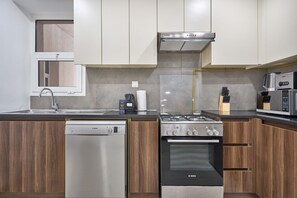 A modern kitchen with a Bosch dishwasher, a gas stove, and a microwave. - Family-Friendly 2BR in Remraam with Pool View (Dubai)