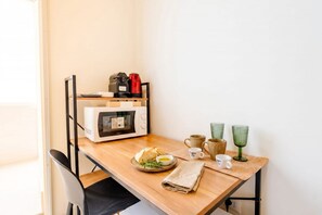 Eine Küchenzeile mit Mikrowelle, Kaffeemaschine und einer Brotschale mit Butter.