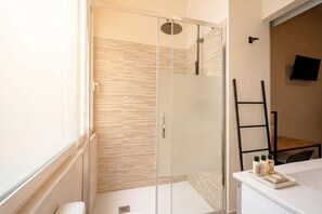Ein modernes Badezimmer mit einer Duschkabine aus Glas, einem weißen Waschbecken und Holzboden.
