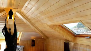 Une pièce aux murs en bois et au plafond incliné, dotée d’une lucarne.