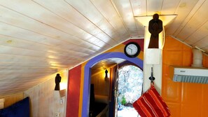A room with wooden walls, a clock, a statue, and a red bag hanging on the wall. - ‘El Nido De Somiedo’ Apartment with Mountain Views, Terrace, and Garden (Las Viñas)