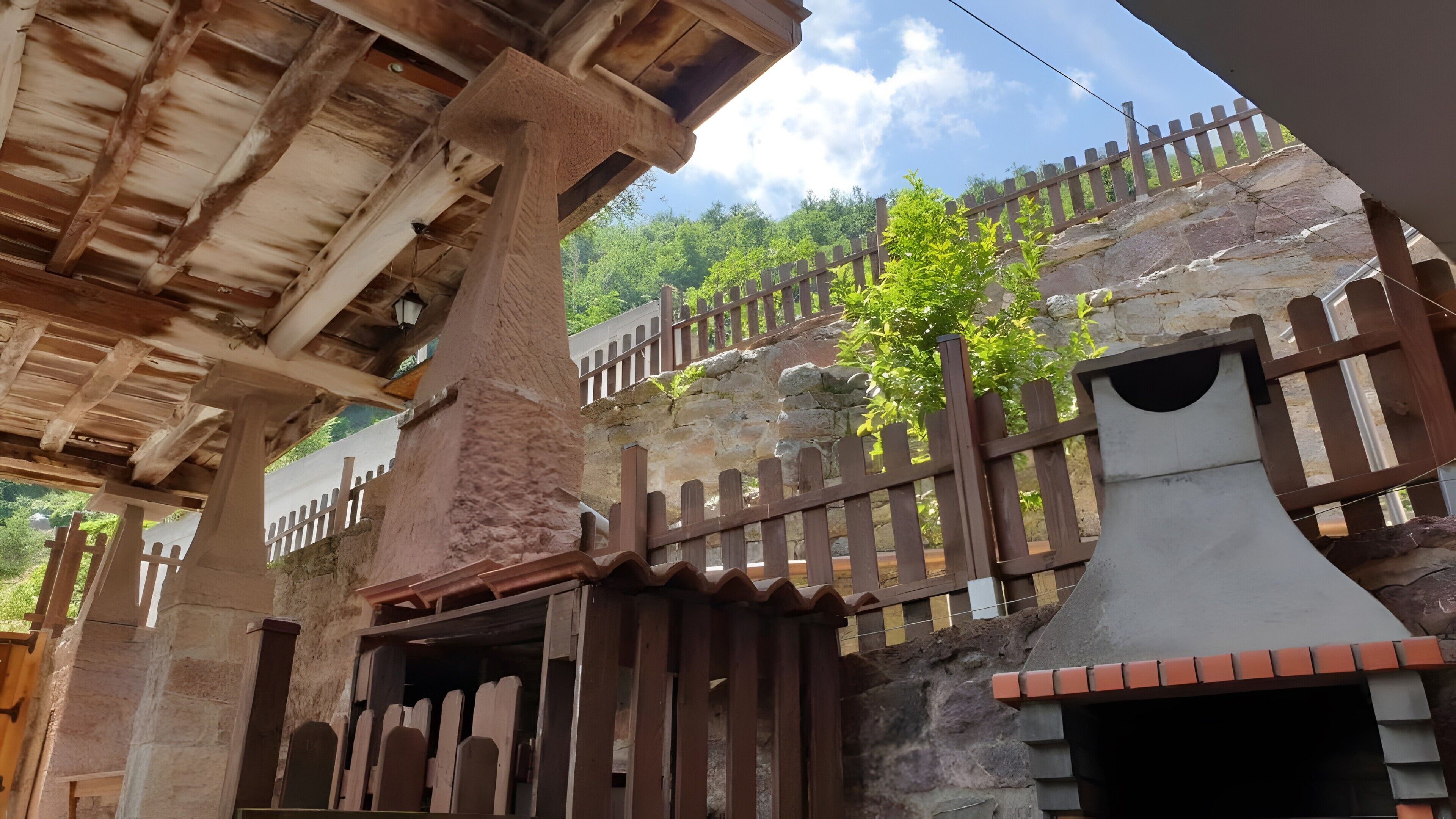 Un edificio rústico de piedra con una cerca de madera y una escalera de madera.