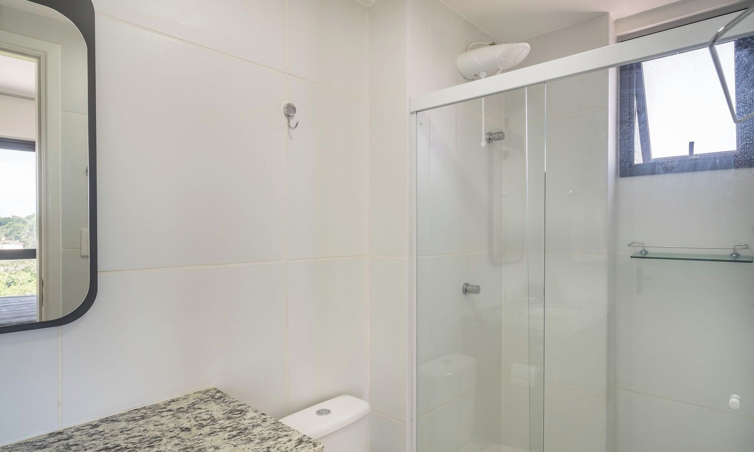 A bathroom with a glass shower enclosure, a marble countertop, and a toilet.
