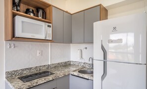 Cozinha equipada com micro-ondas, geladeira de aço inoxidável, bancada de granito e fogão embutido.