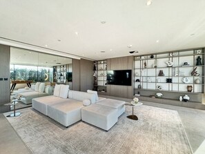 Un salon moderne avec un canapé d’angle, un téléviseur à écran plat et un meuble mural décoratif.