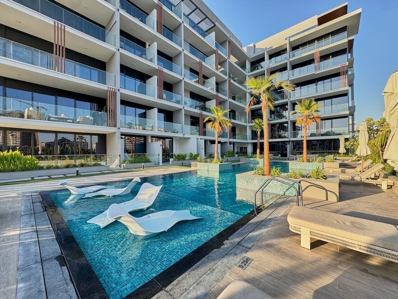 Un hôtel moderne doté d’une piscine, de nombreux balcons et d’un espace extérieur aménagé pour s’asseoir.
