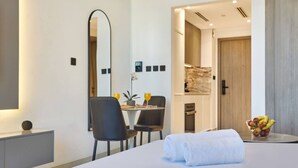 A hotel room with a bed, a desk with a chair, a mirror, and a fruit bowl. - Chic Studio | Pool View Balcony | Avelon Arjan (Dubai)