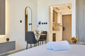 Ein Hotelzimmer mit Bett, Schreibtisch mit Stuhl, Spiegel und Obstschale.