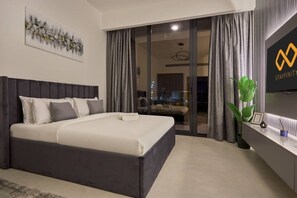 A modern bedroom with a large bed, a flat-screen TV, and a sliding glass door leading to a balcony. - Chic Studio | Pool View Balcony | Avelon Arjan (Dubai)