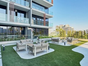 Un espace de vie extérieur moderne, doté de plusieurs coins salon et d’une pelouse bien entretenue.