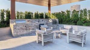 An outdoor patio with a built-in grill and seating area. - Chic Studio | Pool View Balcony | Avelon Arjan (Dubai)