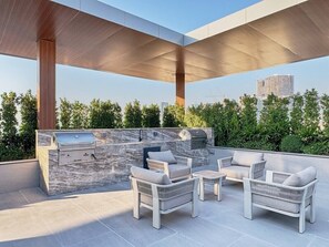 Eine Terrasse im Freien mit Grill und Sitzgelegenheit.