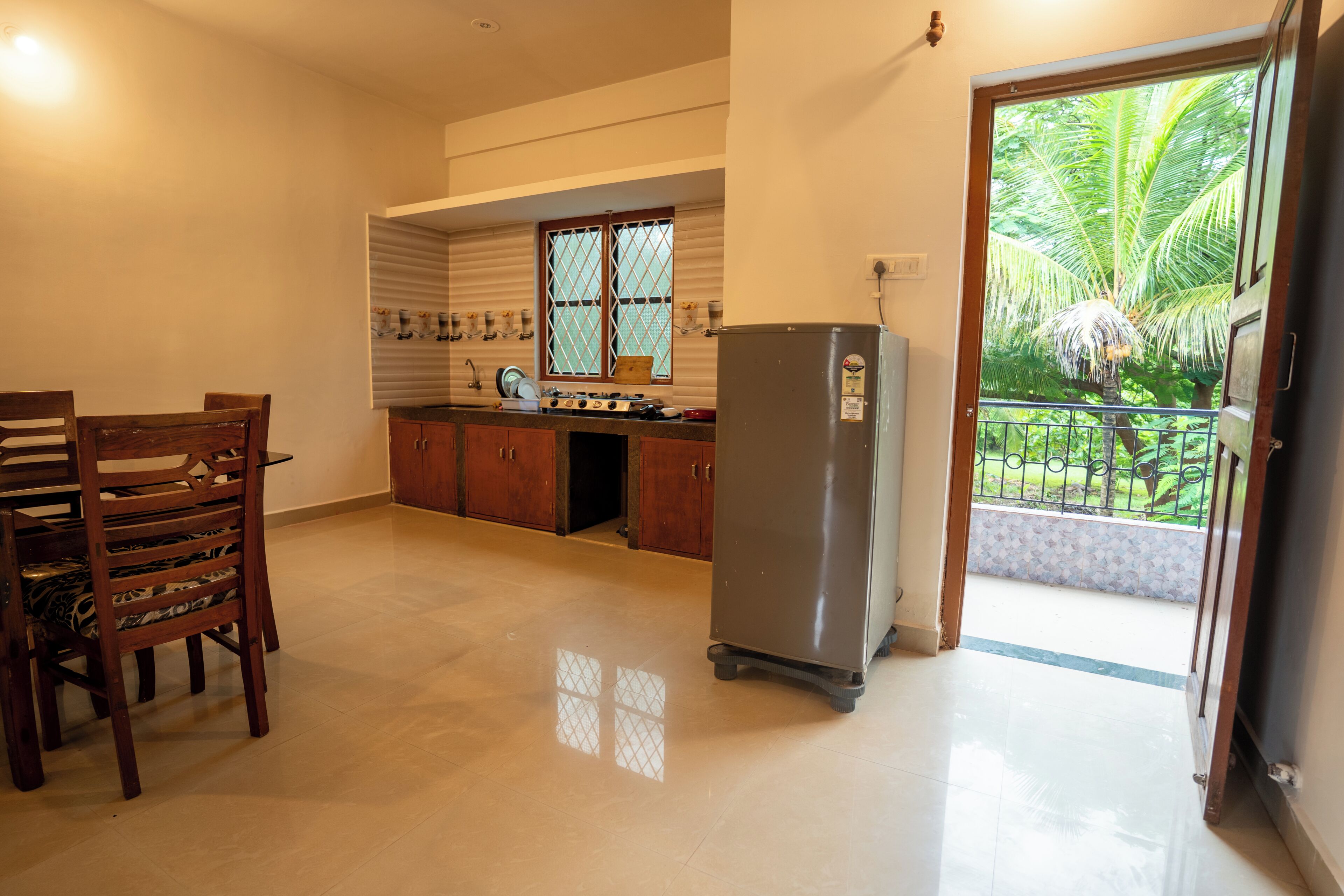 A kitchen with a dining table and chairs, a refrigerator, and a window with blinds.